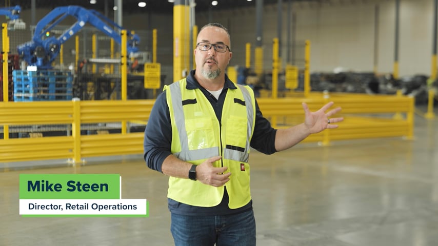 Relogistics employee standing inside Reverse Logistics Center gesturing with hand as a tour guide