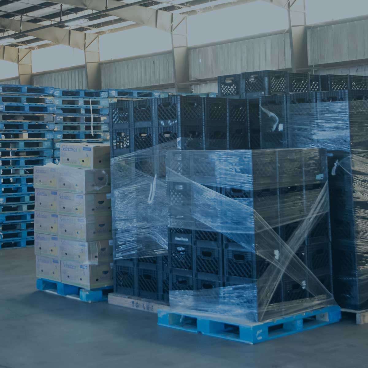 Pallets and plastic crates stacked in a warehouse, showcasing efficient inventory management and optimized space utilization in logistics.