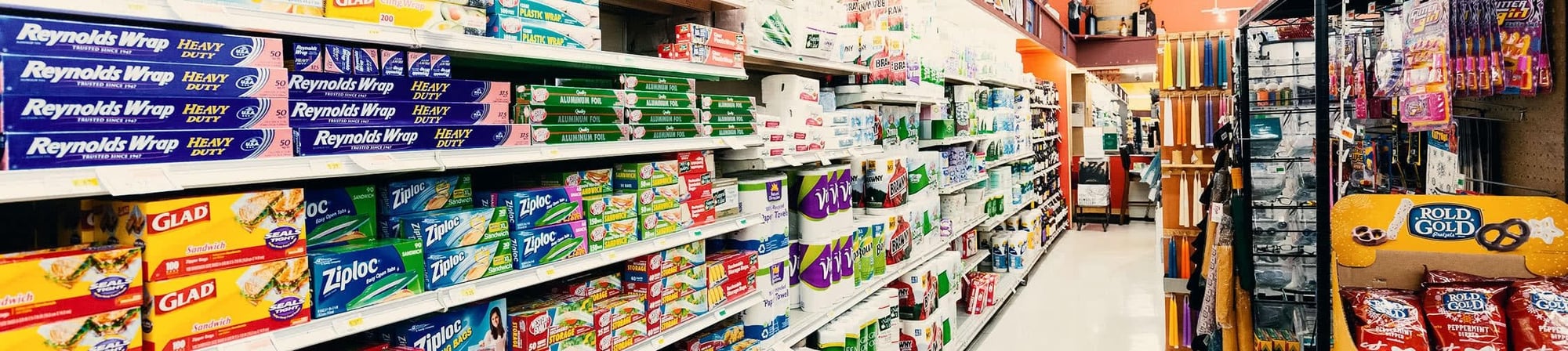 Aisle in retail store displaying various packaging products, including Reynolds Wrap, Glad, and Ziploc, emphasizing the diversity of reusable materials for efficient supply chain management.