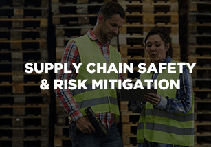 Two individuals in safety vests discussing supply chain safety and risk mitigation, with a backdrop of stacked pallets, emphasizing logistics solutions and operational efficiency.