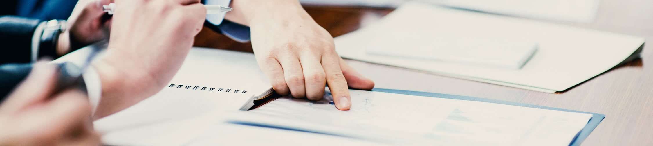 Hands pointing at a document on a table, emphasizing collaboration and data analysis in logistics reporting and optimization. Hands pointing at a document on a table, emphasizing collaboration and data analysis in logistics reporting and optimization.