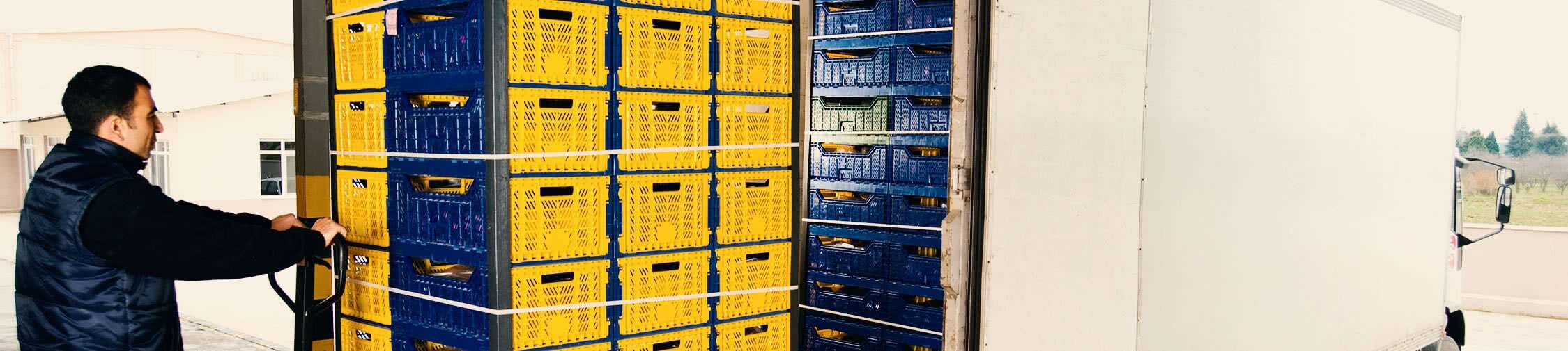Man handling stacked yellow and blue reusable totes in a truck, emphasizing efficient tote management and tracking in the supply chain.
